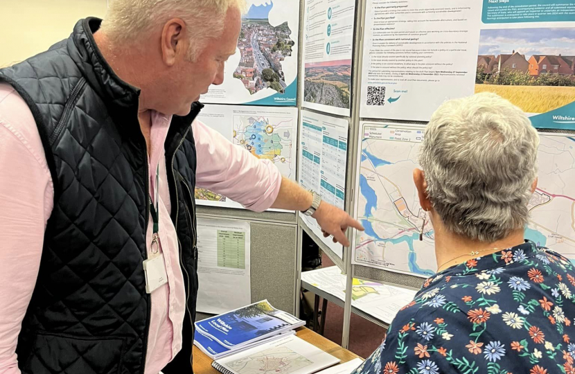 Nic pointing at an information board, informing a member of the public.