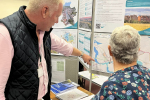 Nic pointing at an information board, informing a member of the public.