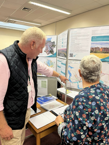 Nic pointing at an information board, informing a member of the public.